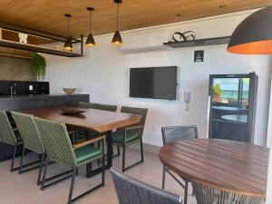 a dining room with a table and chairs and a tv at UMI Flats - Intermares by Refúgio Hospedagens in Cabedelo