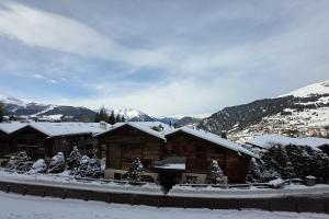 a log cabin in the snow with mountains in the background at Bruyères B22 in Verbier