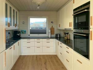 FisterにあるPanorama Cabin With Trails From Door In Ryfylkeの白いキャビネットと窓付きの広いキッチン