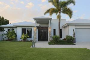 una casa blanca con una palmera en el patio en Serenade Retreat, At Coomera Waters, Gold Coast, en Gold Coast