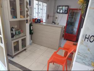 a kitchen with two orange chairs and a counter at Hotel Comercial Neiva EZ in Neiva