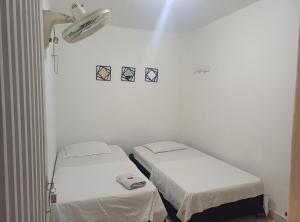 two beds in a room with white walls at Hotel Comercial Neiva EZ in Neiva