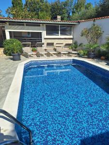 a large blue swimming pool next to a house at Apartment with private pool and arbor in Malinska