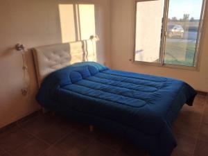 een blauw bed in een kamer met een raam bij Mi Descanso in Balneario Claromecó
