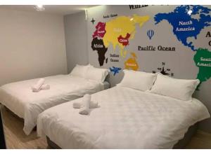 two beds in a room with a world map on the wall at Hotel O ZZZ in Kuah