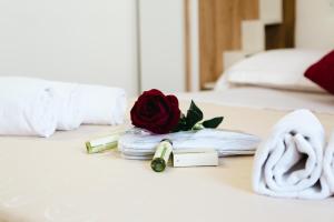 Giù in Calabria B&B - Terrazze Italiane Catanzaro Lido في كاتانزارو ليدو: وردة وولاعة على سرير +10 صور