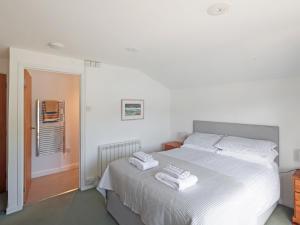 een slaapkamer met een wit bed met handdoeken erop bij Tarquins in Fowey