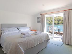 een slaapkamer met een bed en uitzicht op het water bij Tarquins in Fowey