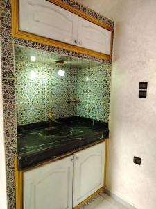 ein Badezimmer mit einem Waschbecken und einer grün gefliesten Wand in der Unterkunft Akwaba lodge in Salé