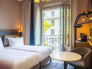 a hotel room with two beds and a table and a window at Grand Hotel des Brotteaux Lyon Ctre - Handwritten Collection in Lyon