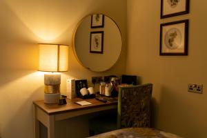 a desk in a hotel room with a mirror and a chair at The Warwick Arms Hotel - The Coaching Inn Group in Warwick