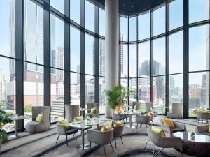 a restaurant with large windows and tables and chairs at Novotel Bangkok Platinum Pratunam in Bangkok