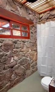 Casa Gaucho hospedate en una reserva natural في Aiguá: حمام حجري مع مرحاض ونافذة