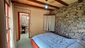 Casa Gaucho hospedate en una reserva natural في Aiguá: غرفة نوم بسرير في جدار حجري