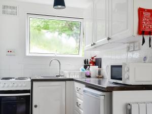 eine Küche mit weißen Geräten und einem Fenster in der Unterkunft 5 The Glade in Bude