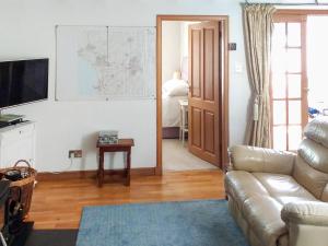 un soggiorno con un divano e una televisione di Honeysuckle Cottage a Springside