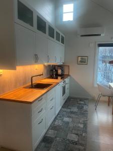 een keuken met witte kasten en een spoelbak bij Breathe - Seafront Hideaway in Skrollsvika