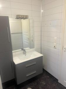 een witte badkamer met een wastafel en een spiegel bij Breathe - Seafront Hideaway in Skrollsvika