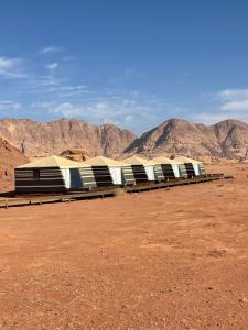 a building in the desert with mountains in the background at Discover the life of Wadi Rum camp in Wadi Rum