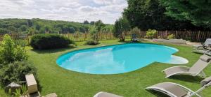 ein großer blauer Swimmingpool in einem Hof mit Stühlen in der Unterkunft Le Ranch Des Ours in Champagnac-la-Rivière