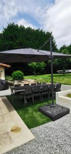 eine Terrasse mit Sonnenschirm und Tischen und Stühlen in der Unterkunft Le Ranch Des Ours in Champagnac-la-Rivière