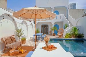 a patio with an umbrella and a pool at Homestay Santoni Mũi Né in Mui Ne