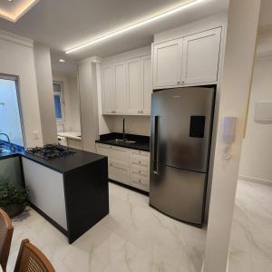 una cocina con nevera de acero inoxidable y armarios blancos en Doce lar, en Itapema