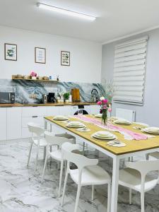 a kitchen with a wooden table and white chairs at Cozy Hostel in Bulgan