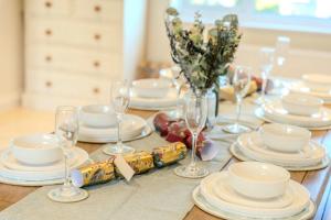 una mesa con platos blancos y copas de vino. en Rowans Stow-on-the-Wold 4 Bed Cotswolds Home, en Stow on the Wold