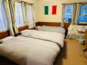 three beds in a room with windows at Echoland Madarao エコーランド斑尾 All en-suite rooms & a free 3-minute shuttle to the ski resort in Madarao Kogen