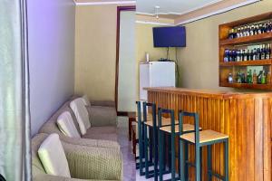 Una cocina con barra, sillas y sofá. en Nilevic Guest House Entebbe, en Entebbe