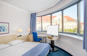 ein Hotelzimmer mit einem Bett, einem Schreibtisch und einem Fenster in der Unterkunft Hotel Erfurt City Center by Leonardo Hotels in Erfurt