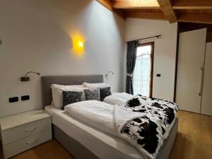 a bedroom with a bed with a black and white blanket at Cèsa Nicole e Patrick in Campitello di Fassa