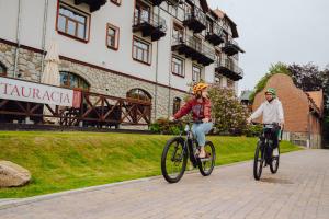 zwei Leute, die mit ihren Fahrrädern eine Straße hinunterfahren in der Unterkunft Hotel Buczyński Medical & SPA in Świeradów-Zdrój