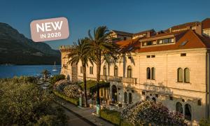 科尔丘拉Aminess Younique Korcula Heritage Hotel的水边有棕榈树的建筑