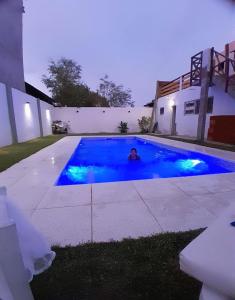 Un hombre está en una piscina por la noche. en Departamento villa Gesell con pileta, en Villa Gesell