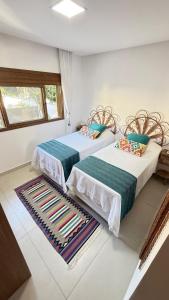 Casa nova em condominio com 4 suites spa e academia في بورتو سيغورو: غرفة نوم بسريرين وسجادة