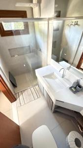 Casa nova em condominio com 4 suites spa e academia في بورتو سيغورو: حمام مزود بحوض ومِرآة