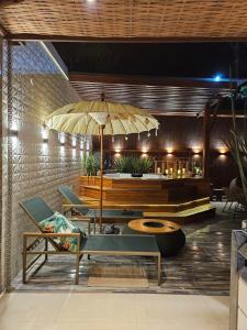 Casa nova em condominio com 4 suites spa e academia في بورتو سيغورو: فناء فيه كراسي وطاولة ومظلة