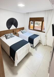 Casa nova em condominio com 4 suites spa e academia في بورتو سيغورو: غرفة نوم بها سريرين ونافذة