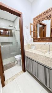 Casa nova em condominio com 4 suites spa e academia في بورتو سيغورو: حمام مزود بمرحاض ومغسلة ومرآة +12 صورة