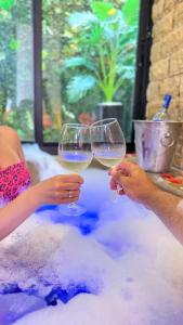two people holding wine glasses in the bath tub at Casinhas do Morro in Morro de São Paulo
