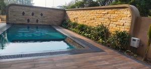a swimming pool in front of a brick wall at Sangath Banquet & Resort in Nadiad