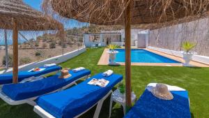 eine Terrasse mit blauen Stühlen und einem Pool in der Unterkunft Villa Diego Torrox by Ruralidays in Torrox