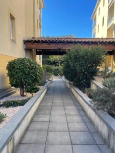 a walkway leading to a building with a bridge at Studio Résidence les Jardins du Musée in Alès
