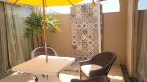 een tafel en stoelen met een parasol op een terras bij Loft Caeté in Araruama