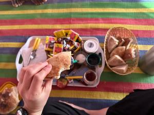 a person holding a sandwich in front of a tray of food at Auberge Tembahjit in Terjit
