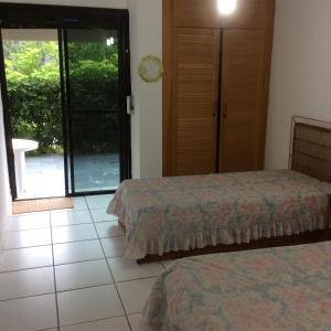 a bedroom with two beds and a sliding glass door at Condomínio Fechado - Enseada - Lazer Total in Guarujá