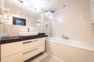 a white bathroom with a sink and a bath tub at Apartament Avignon in Wrocław +23 photos