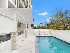 an outdoor swimming pool with chairs and a building at Timi Property in Brisbane